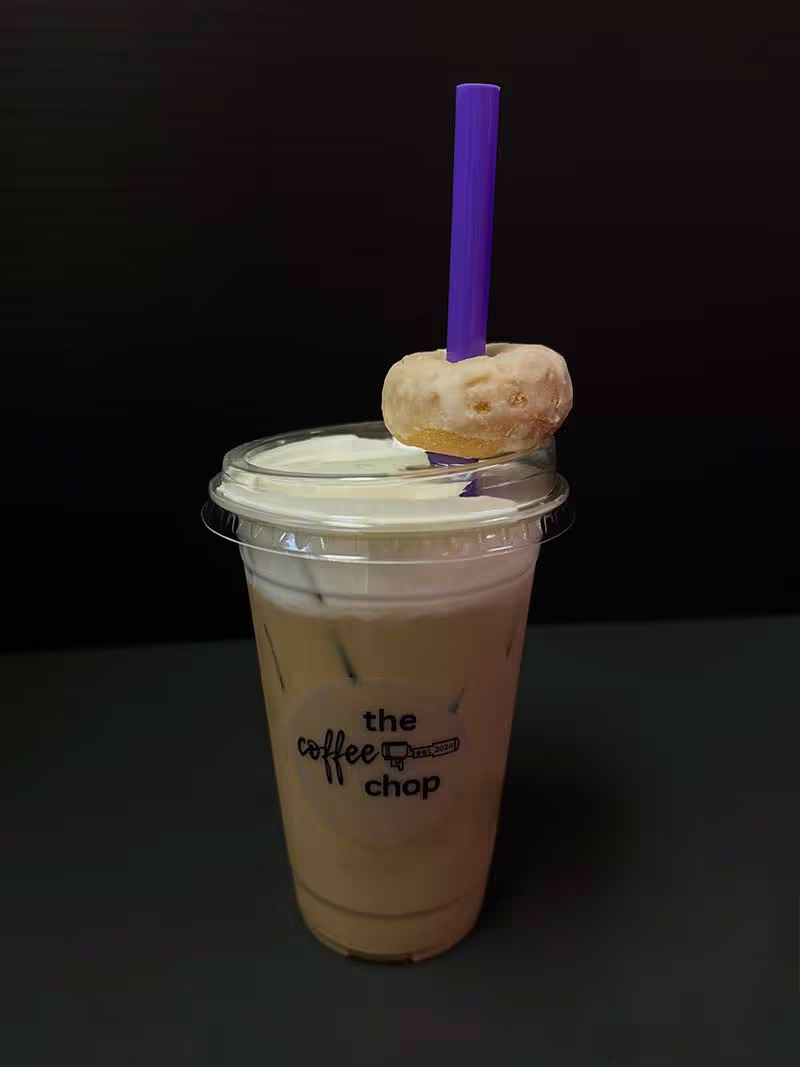 A cup of coffee with a donut on top.