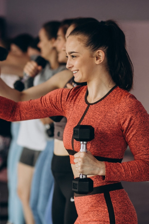 A group of women at CrossFit Ravn Fitness in Førresfjorden, each holding dumbbells and engaged in a workout session.