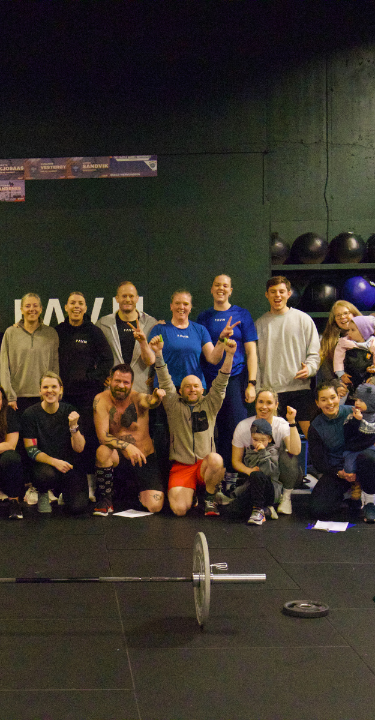 A man and woman exercising together at CrossFit Ravn Fitness in Førresfjorden, RO, showcasing teamwork and fitness.