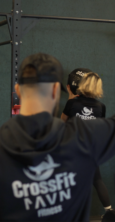 A group of people exercising in a gym, with one individual using a rowing machine at CrossFit Ravn Fitness in Førresfjorden, RO.