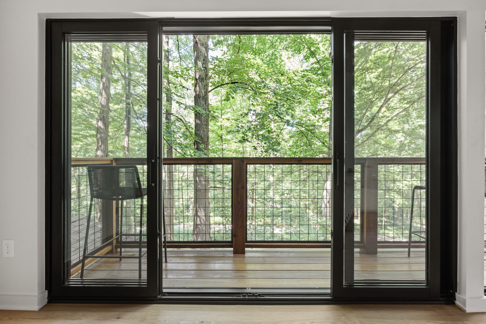 Sliding glass doors to wooded balcony – Indoor-outdoor living space created in a 1970s home addition by Emergent Construction.