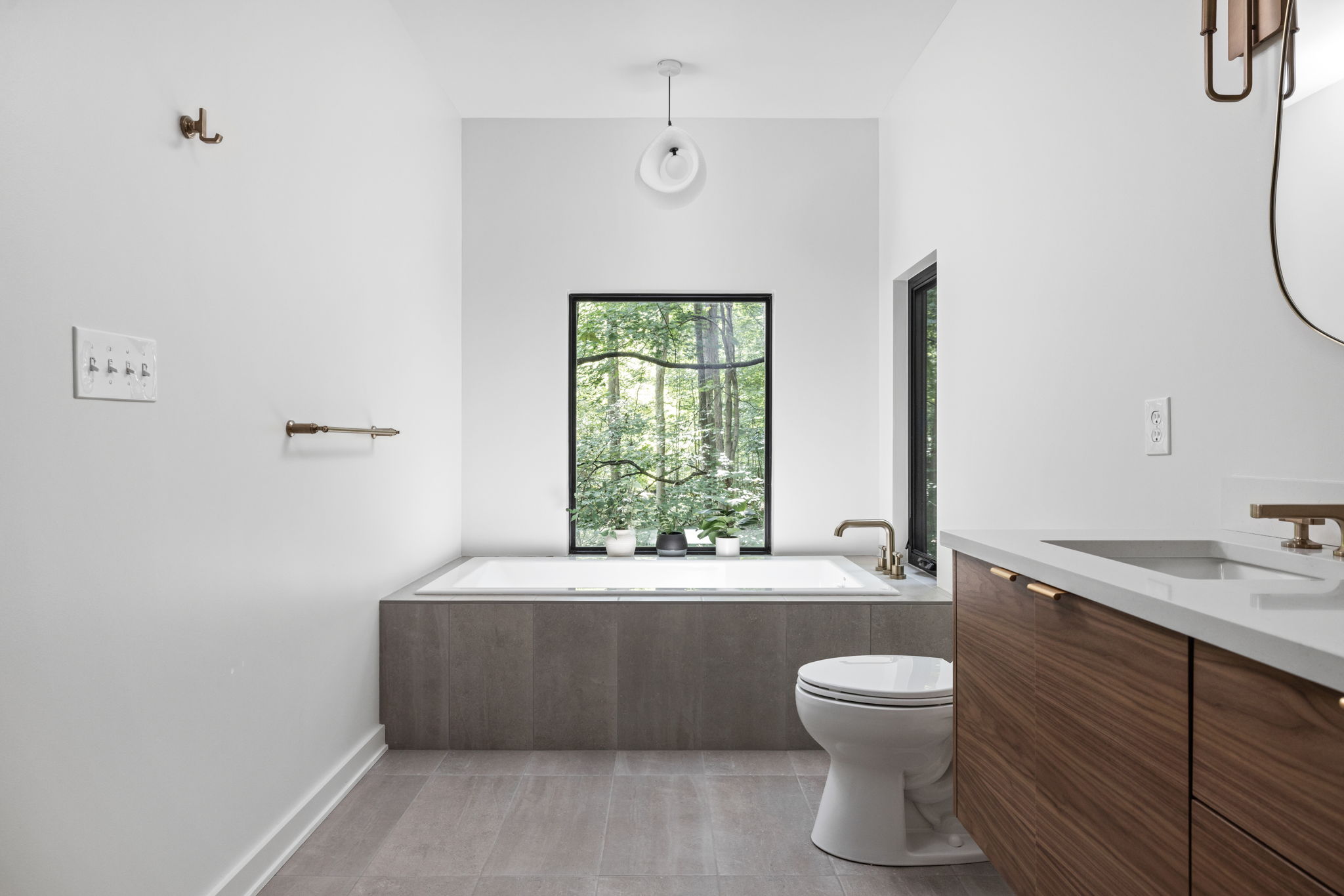 Spa-inspired bathroom with soaking tub and modern wood vanity – Primary suite addition designed and built by Emergent Construction.