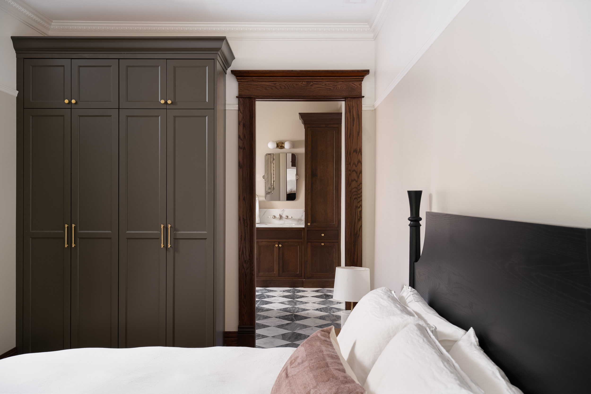 Renovated Victorian bedroom with dark wood built-in cabinetry, hardwood floors, and neutral finishes.