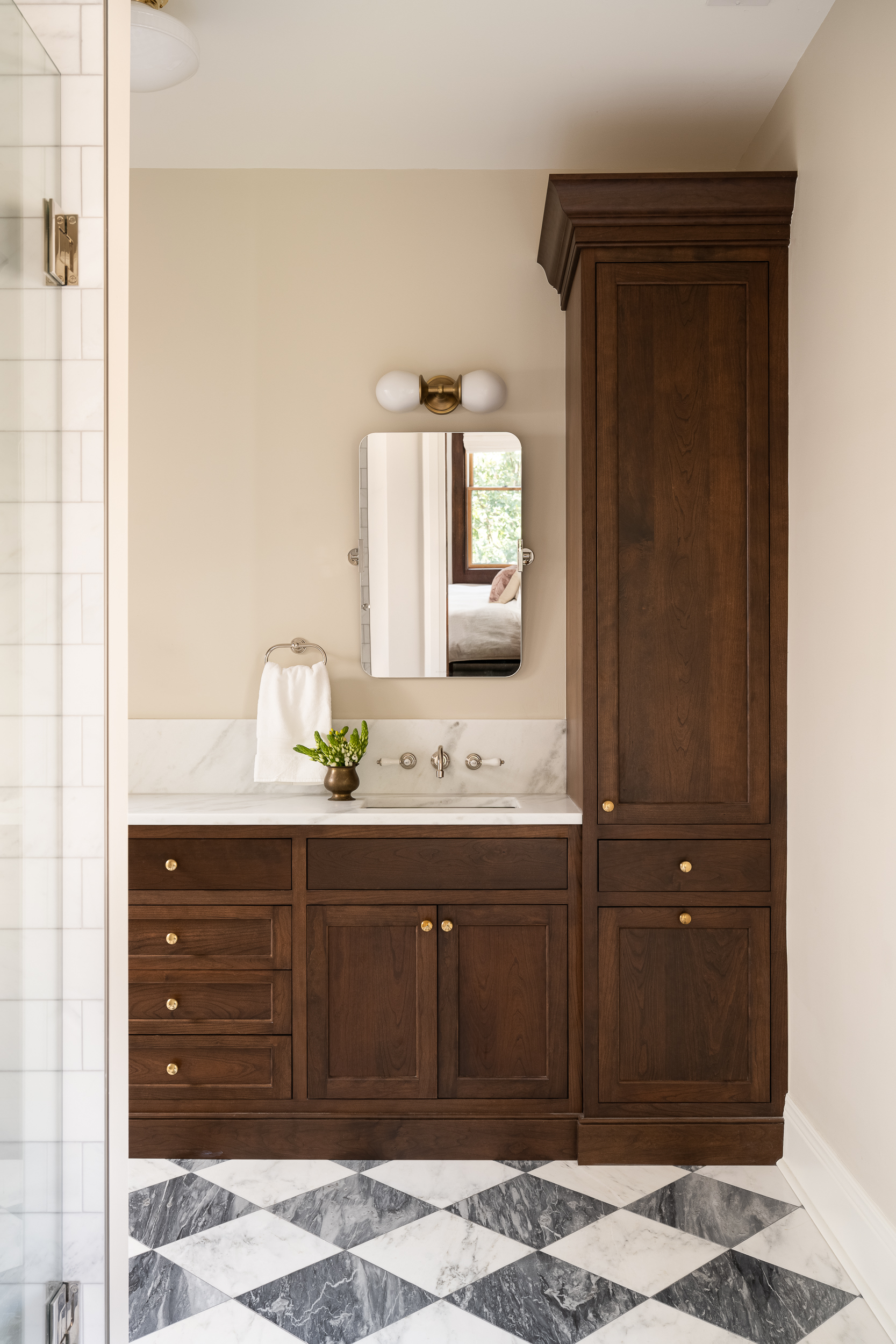Historic bathroom renovation with dark wood vanity, marble countertop, and black-and-white patterned tile flooring.