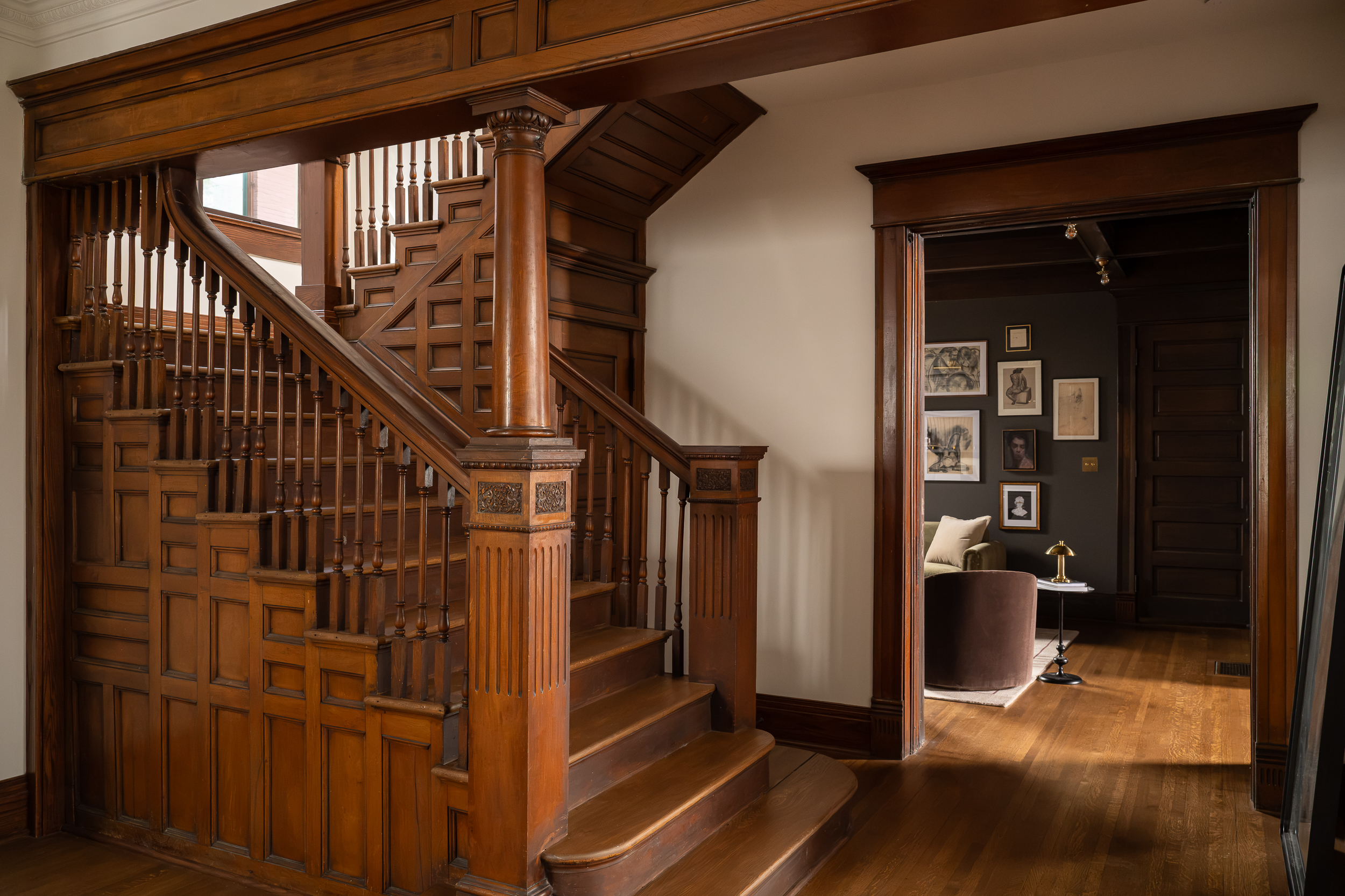 Restored Victorian staircase featuring intricate original woodwork, decorative posts, and hardwood floors.
