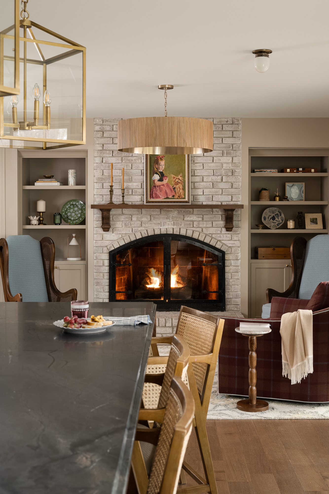 Open-concept living and dining space featuring a brick fireplace, built-in shelving, and warm wood finishes.
