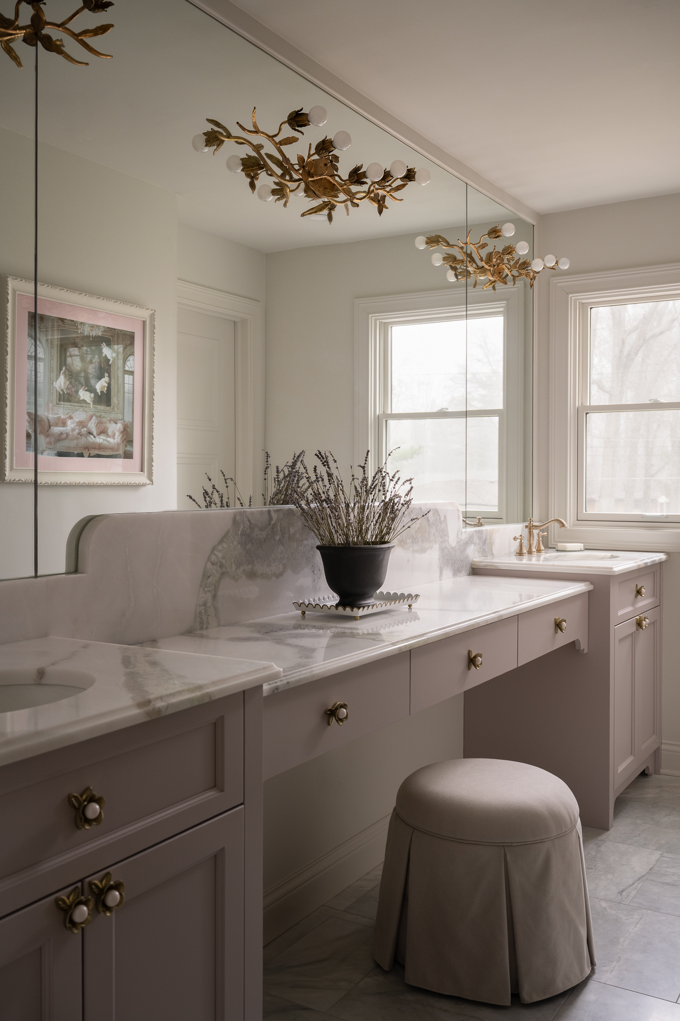 Bright laundry room with custom cabinetry, white countertops, large windows, and decorative brass lighting.