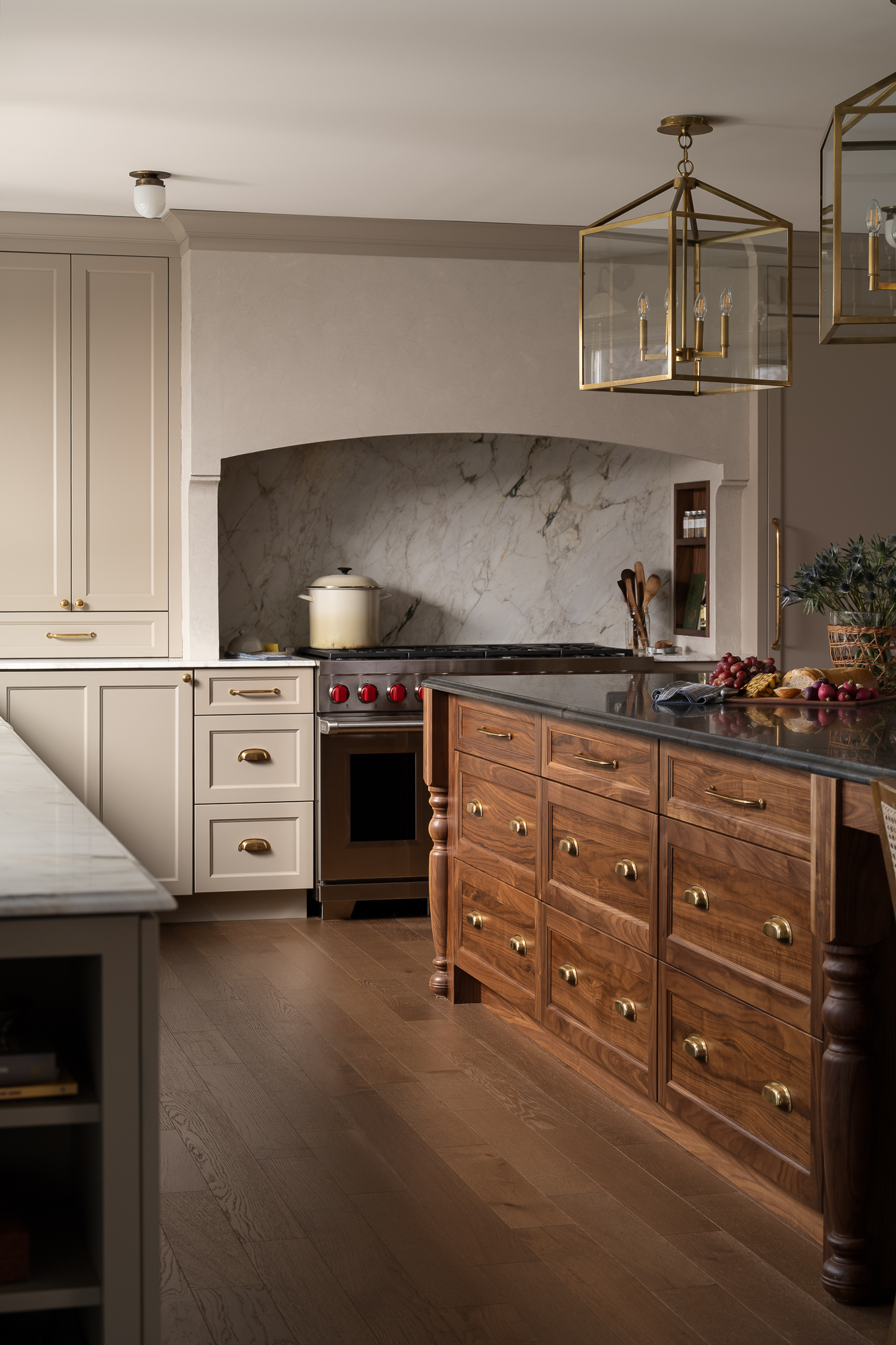 Custom kitchen renovation featuring cream cabinetry, a natural wood island, brass pendant lighting, and a statement range hood.