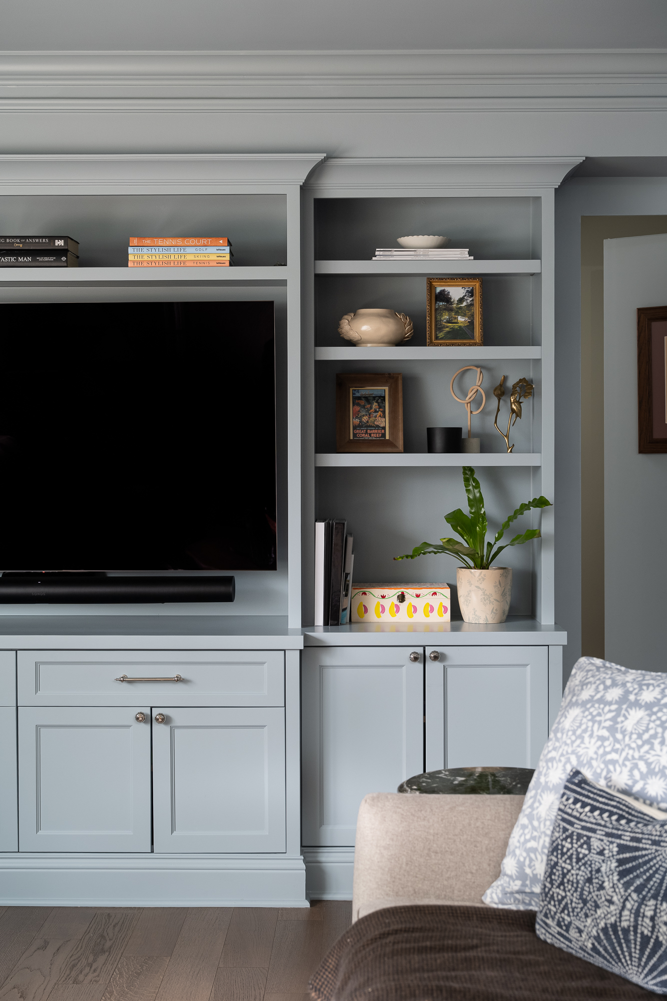 Family living room featuring custom blue-gray built-in cabinets, open display shelving, and an integrated television.