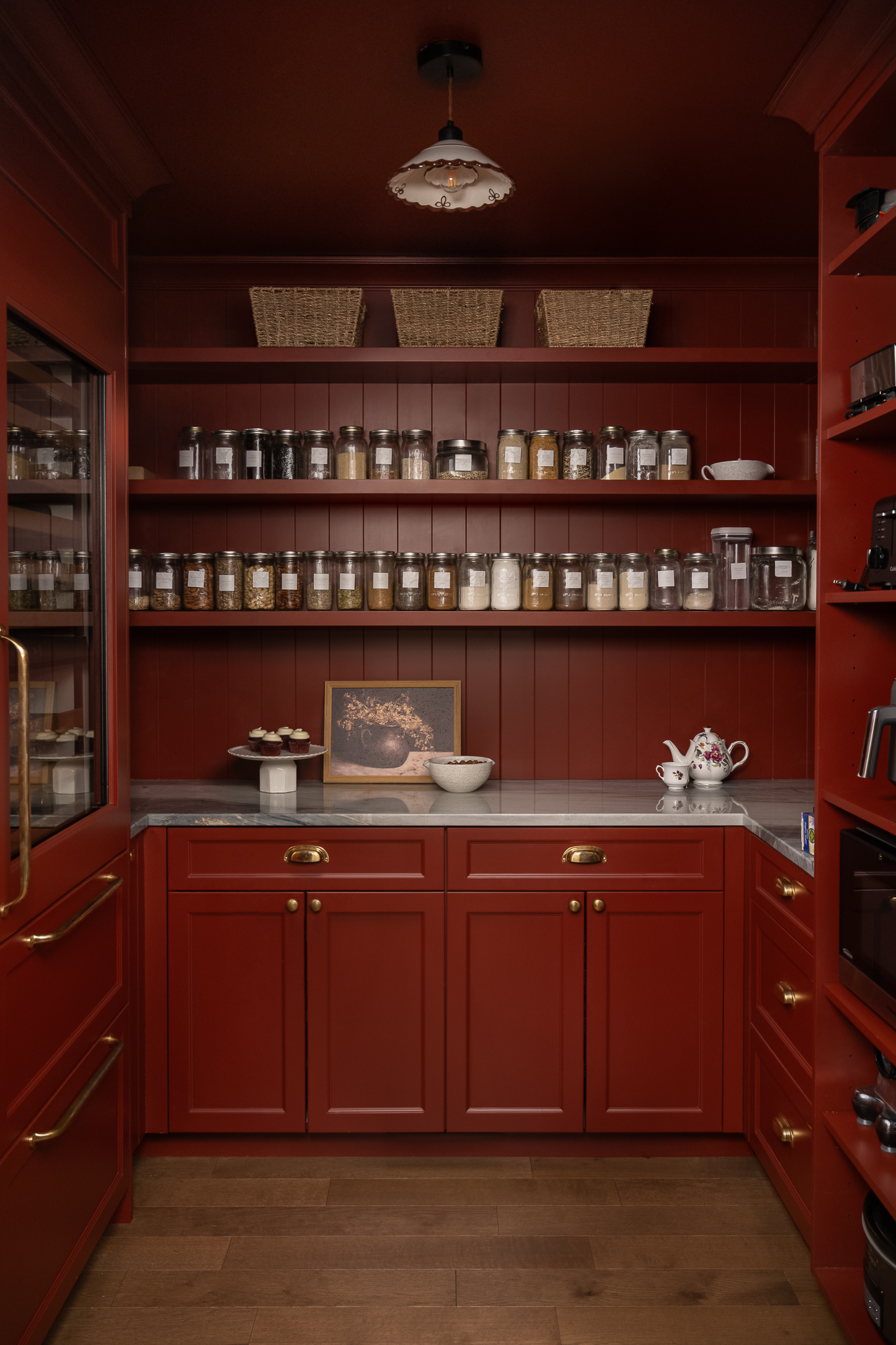 Bold red pantry featuring floor-to-ceiling custom cabinetry, open shelving, and organized storage.