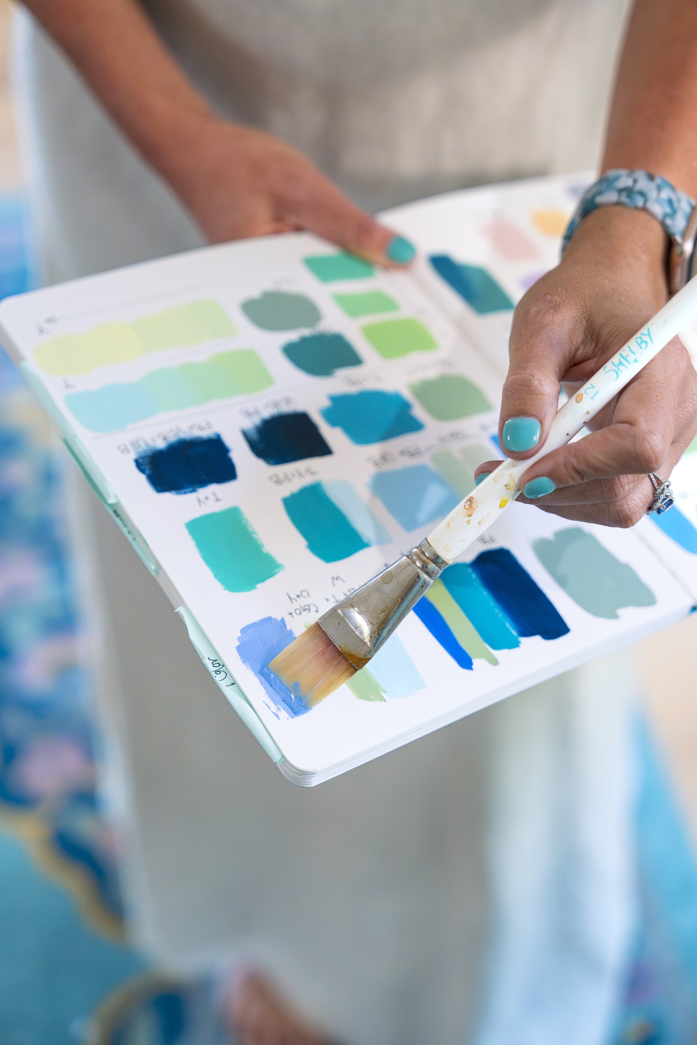 Shelby Dillon demonstrates a palette of colors with her hand and brush.