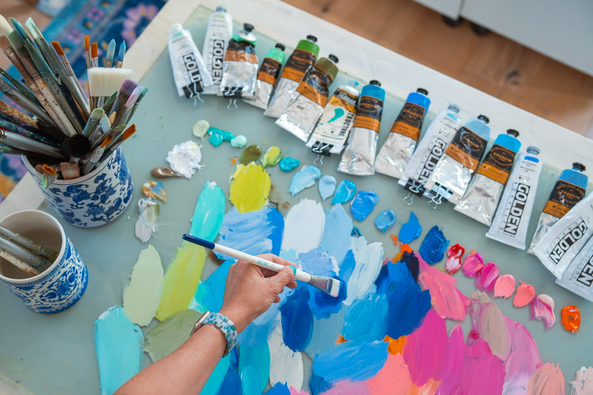 This image shows Shelby Dillon's paint palette in action as she mixes shades of blue to prepare for her canvas.