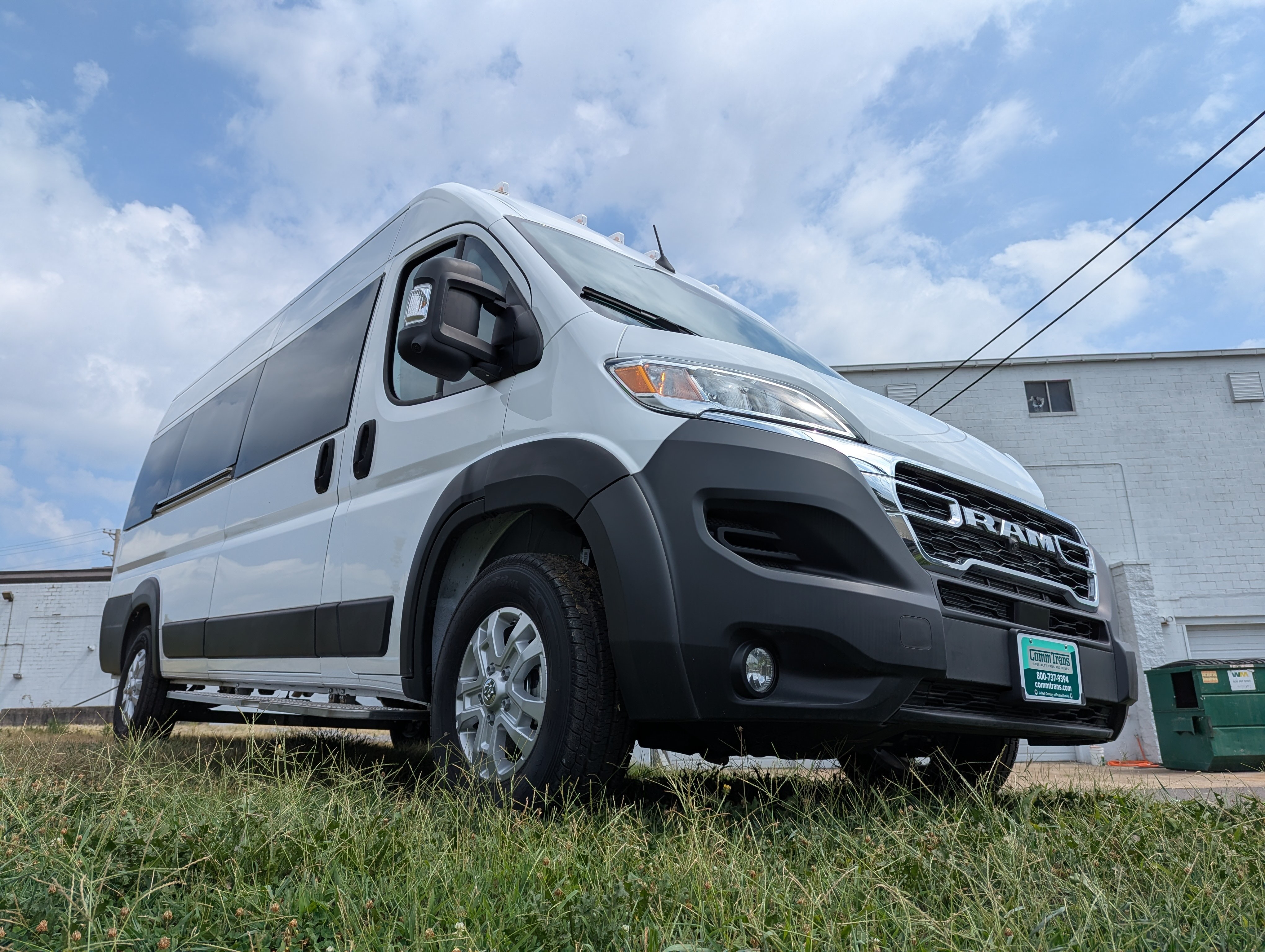 White RAM van parked on grass with a cloudy sky and white building in the background.