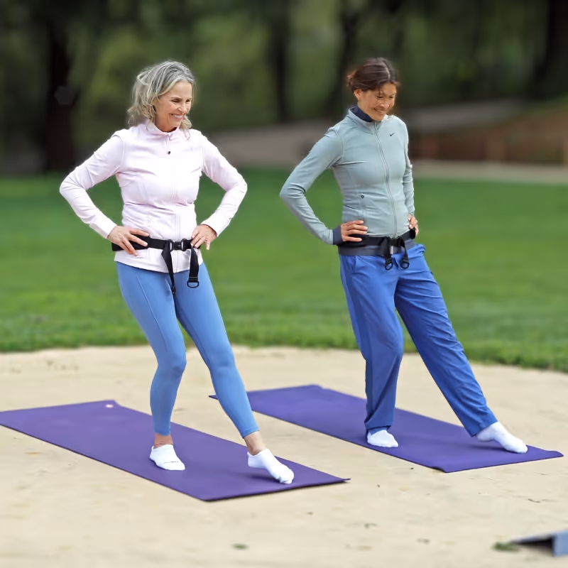 Two women exercising outdoors while wearing their Osteoboost devices