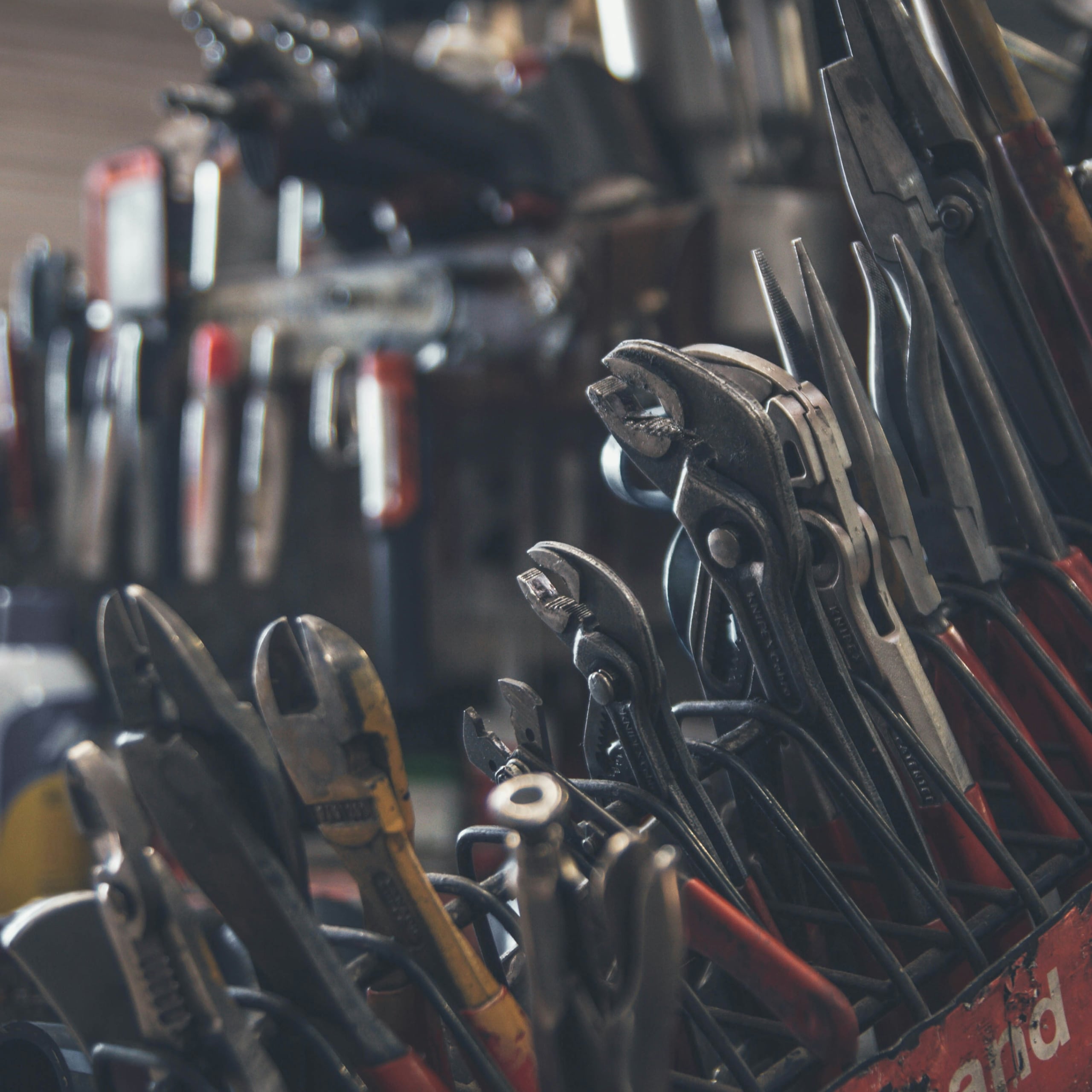 Various hand tools including pliers, wrenches, and wire cutters organized in a red tool holder.