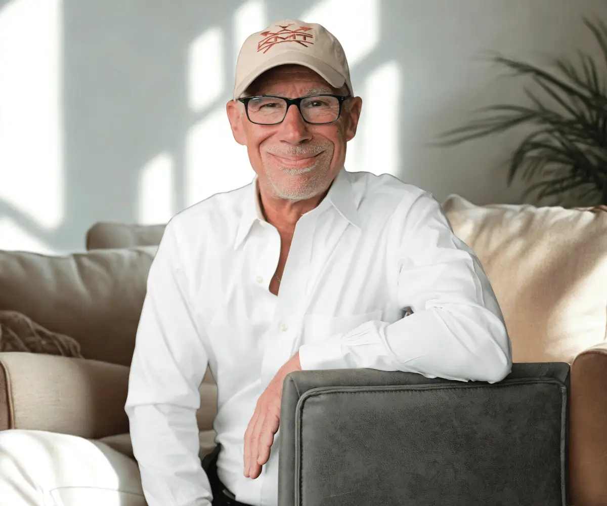 Dr. Robert Kiltz wearing a white shirt and cap, sitting comfortably at home, embodying health, wellness, and balance.