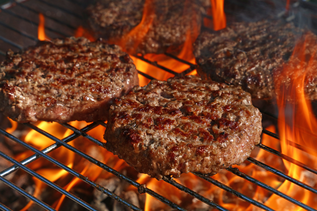 Close up beef or pork meat barbecue burgers for hamburger prepared grilled on bbq fire flame grill, high angle view