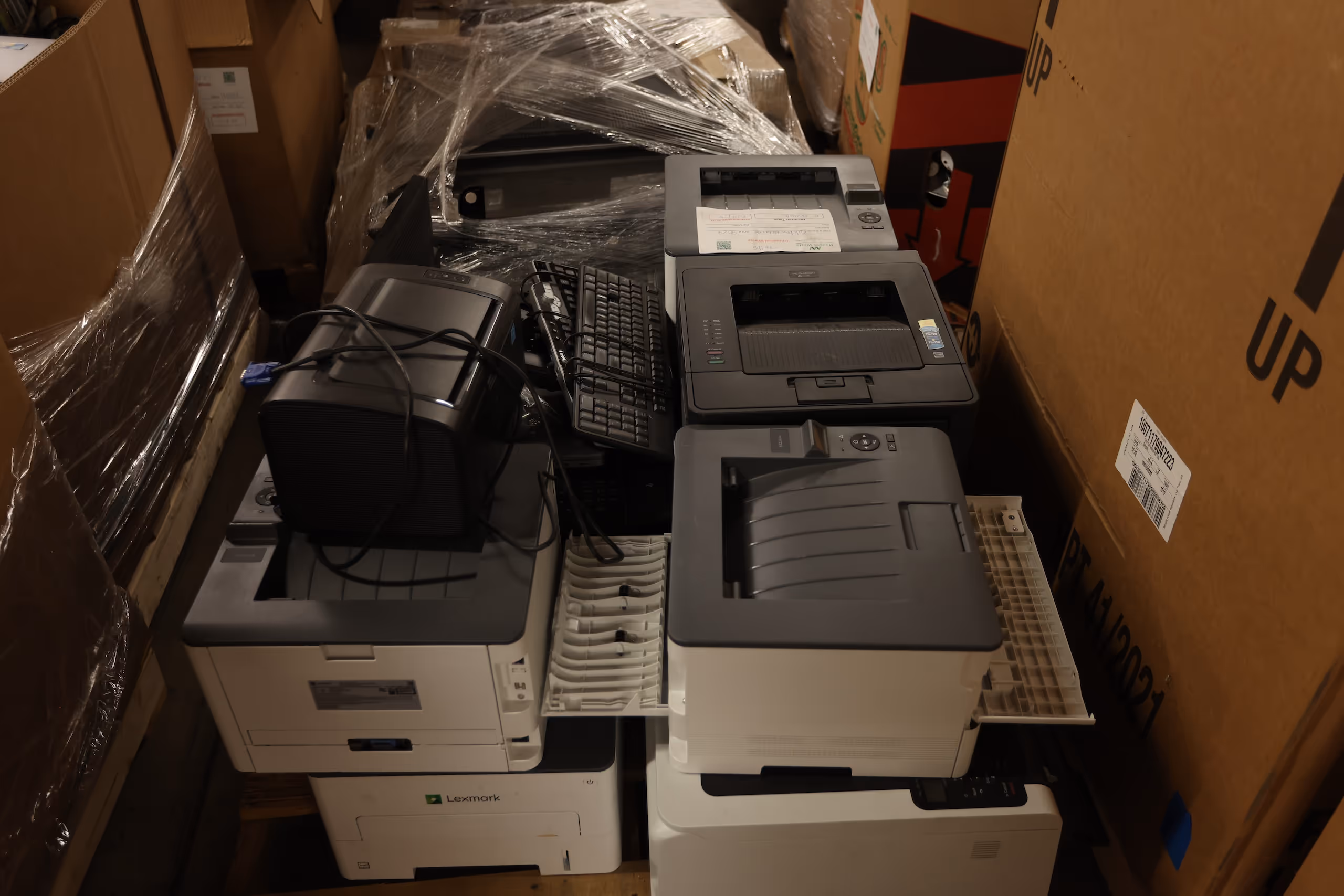 Stack of old printers, keyboards, and office electronics prepared for e-waste recycling.