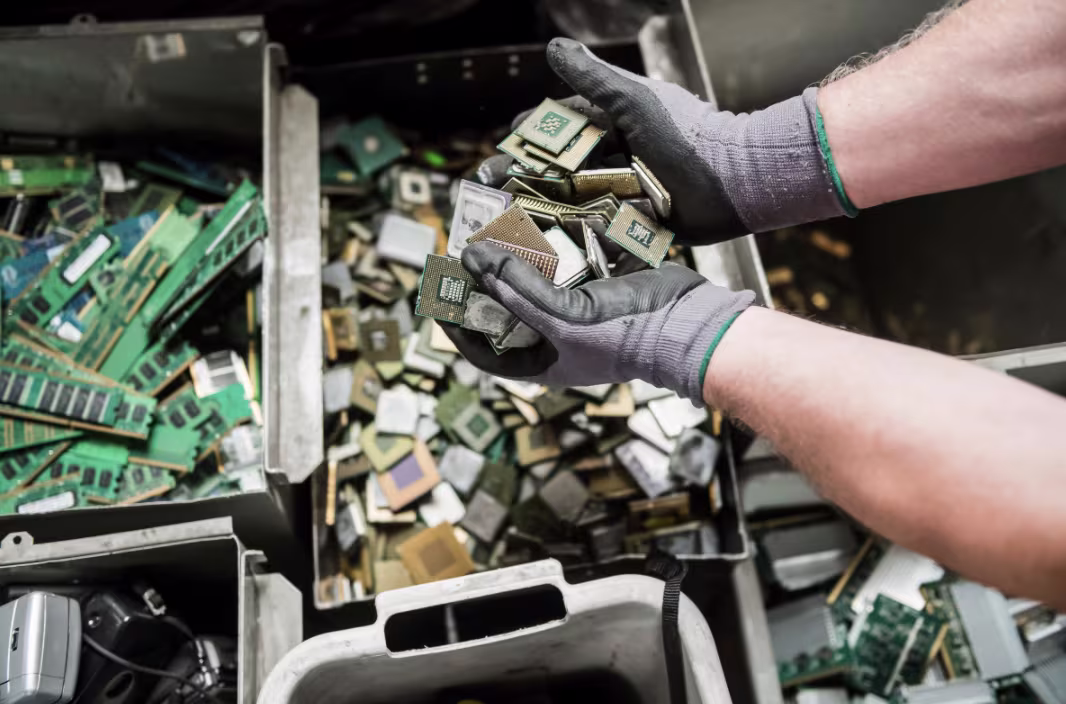 Worker's hands sorting e-waste materials for recycling