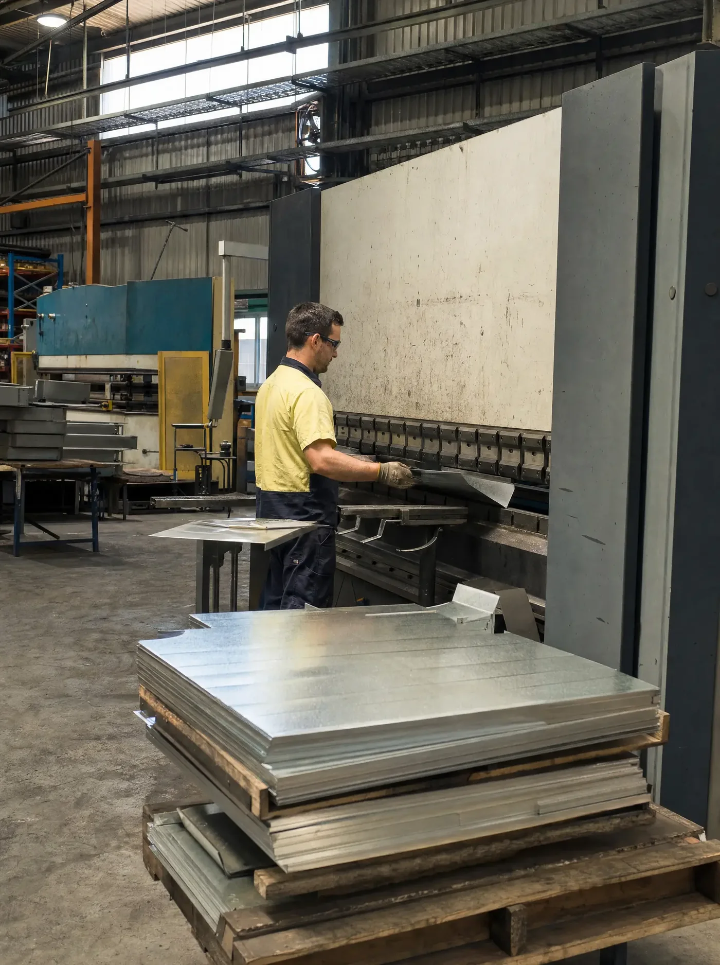 Operator feeding steel sheet into a folding machine in the sheet-metal shop