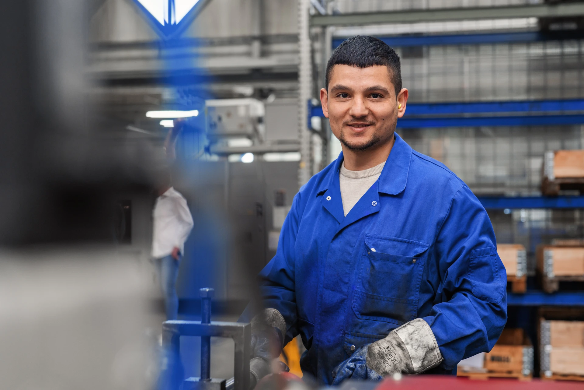 Produktionsmitarbeiter bei Graewe trägt blaue Arbeitskleidung und arbeitet in der Werkhalle