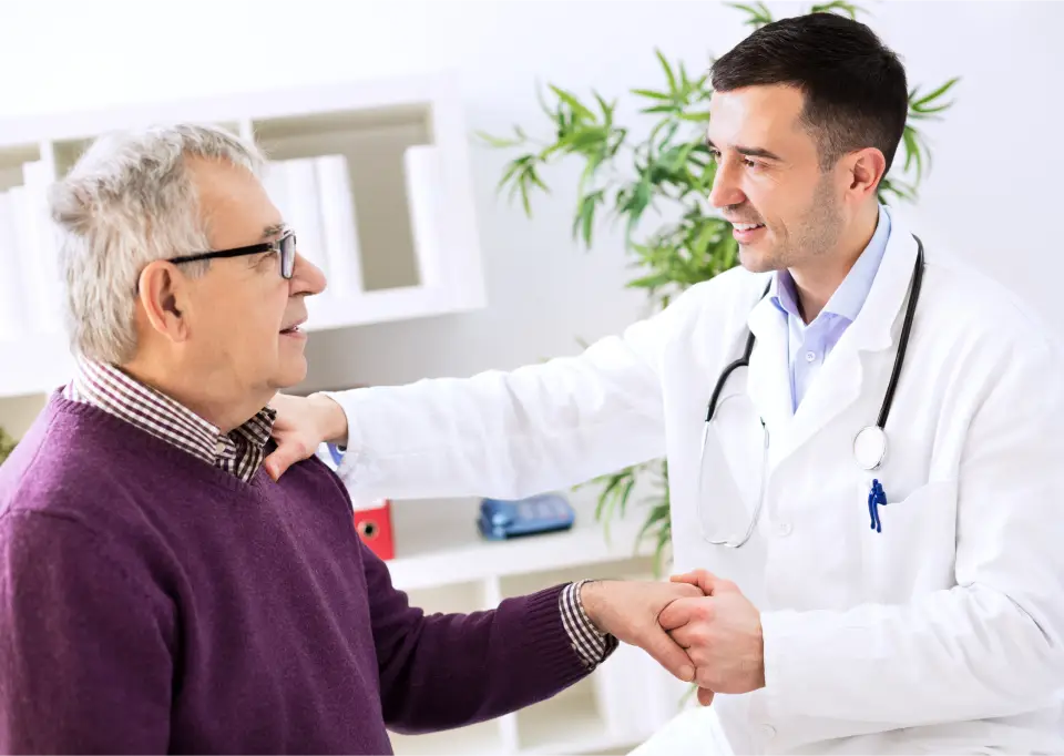 Ein Arzt reich einem Patienten die Hand und hält ihn bestätigend an der Schulter