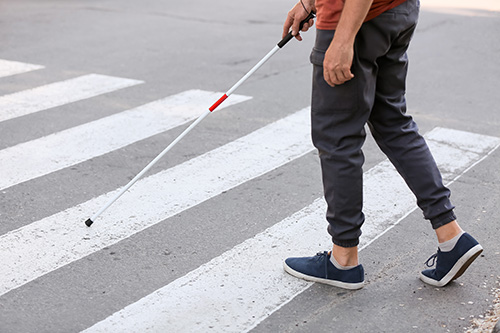 白杖持った人物が横断歩道を渡っている様子の足元