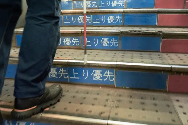 白杖を使って階段を上る人