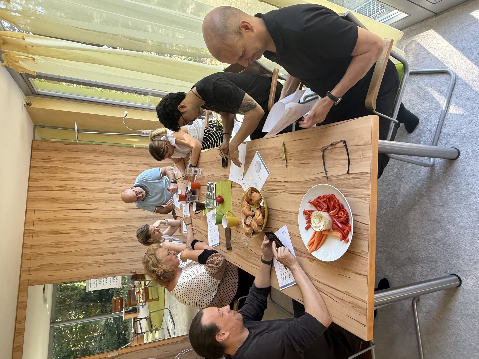 Gemeinsames Mittagessen am langen Tisch unter dem Glasdach