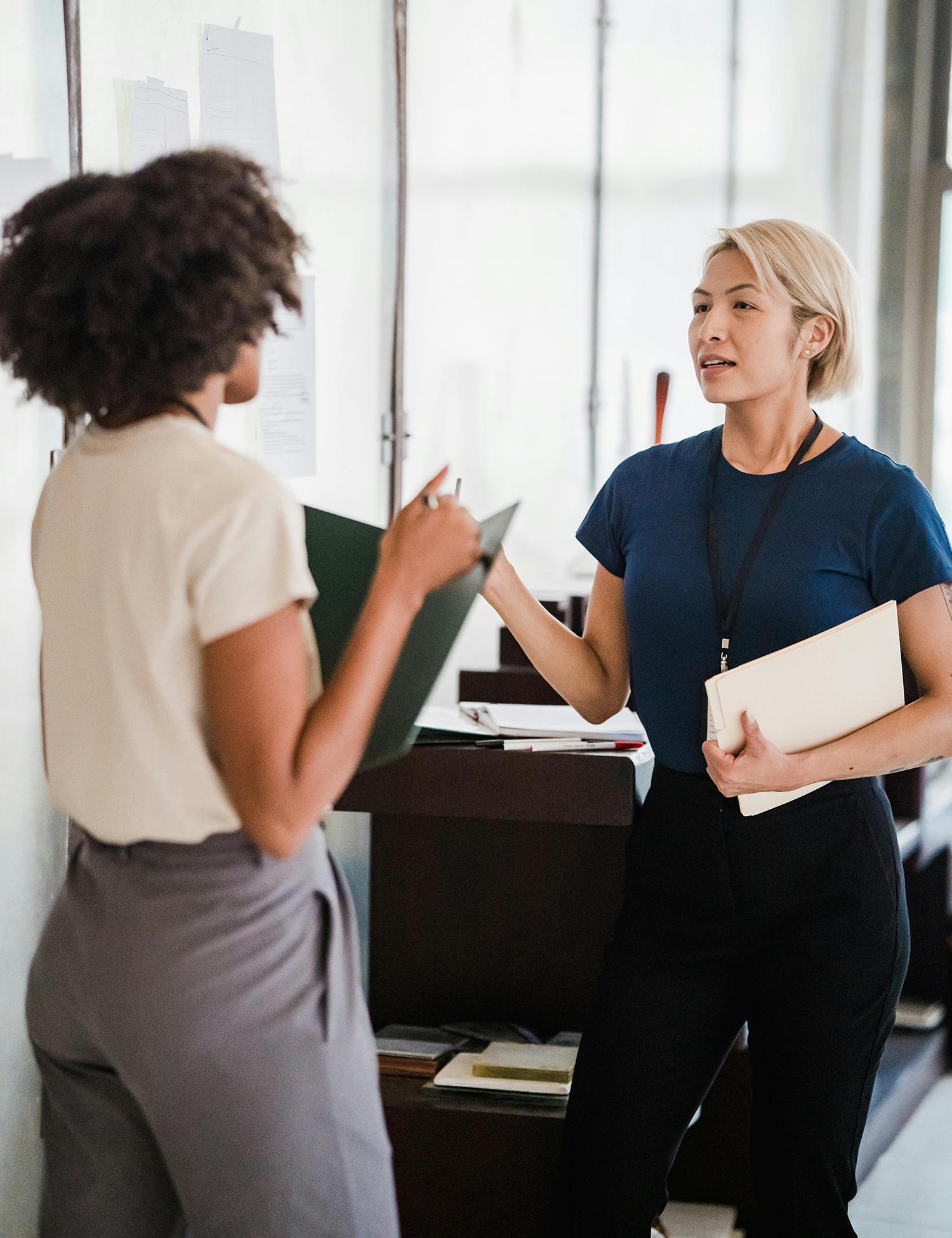 Two women having a friendly conversation in a modern office.