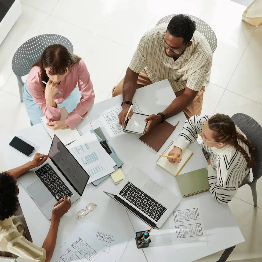 a group of people sitting at a circular table, working together