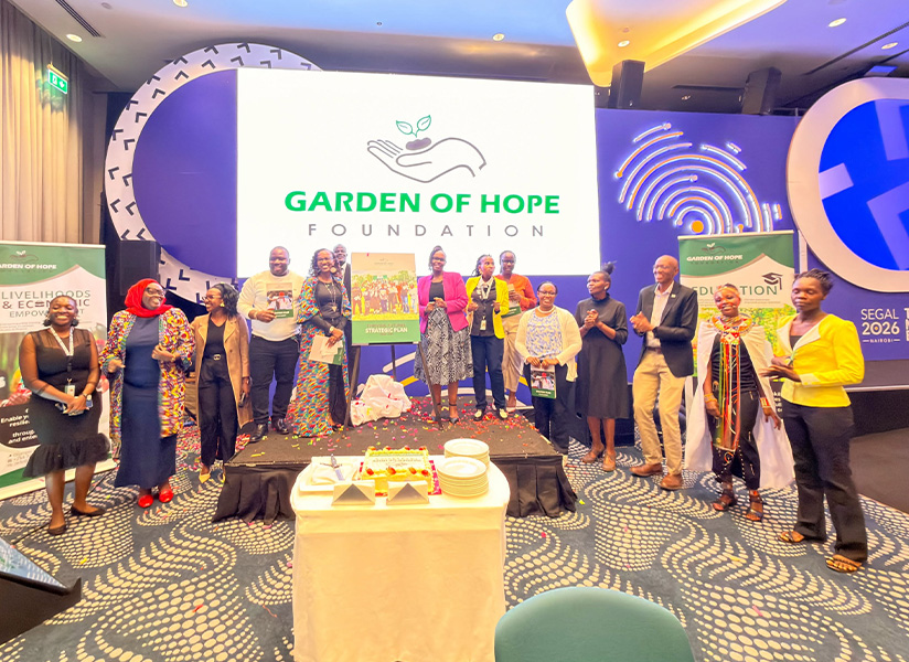 Staff and guests gather on stage beneath a Garden of Hope Foundation banner at an anniversary celebration.