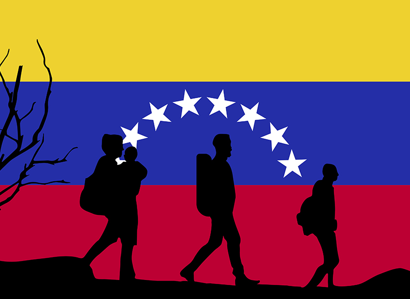Silhouettes of migrating families carrying children and bags walk in front of the Venezuelan flag.