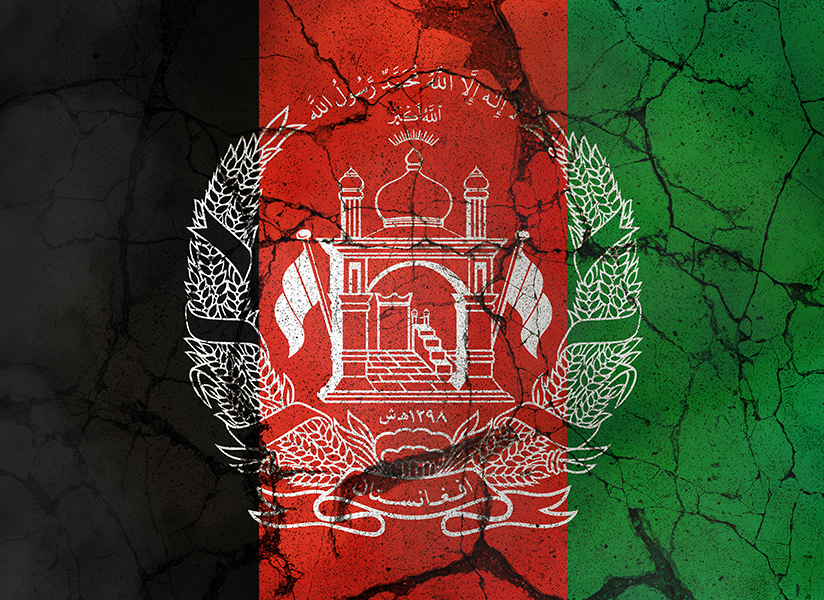 The flag of Afghanistan on a dark, cracked surface.