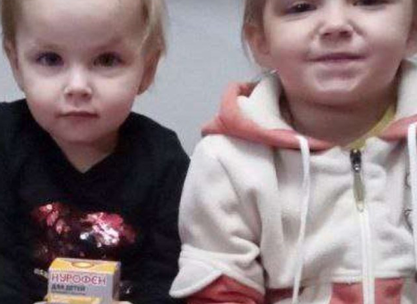 Three young children sit together holding small juice boxes.