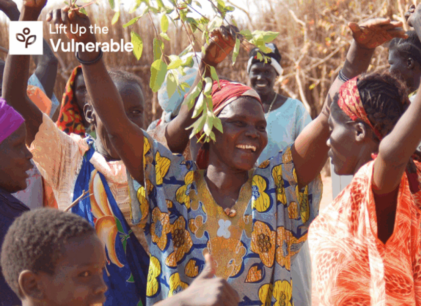 Joyful women raise their arms and wave green branches in celebration, with the Lift Up the Vulnerable logo in the corner.