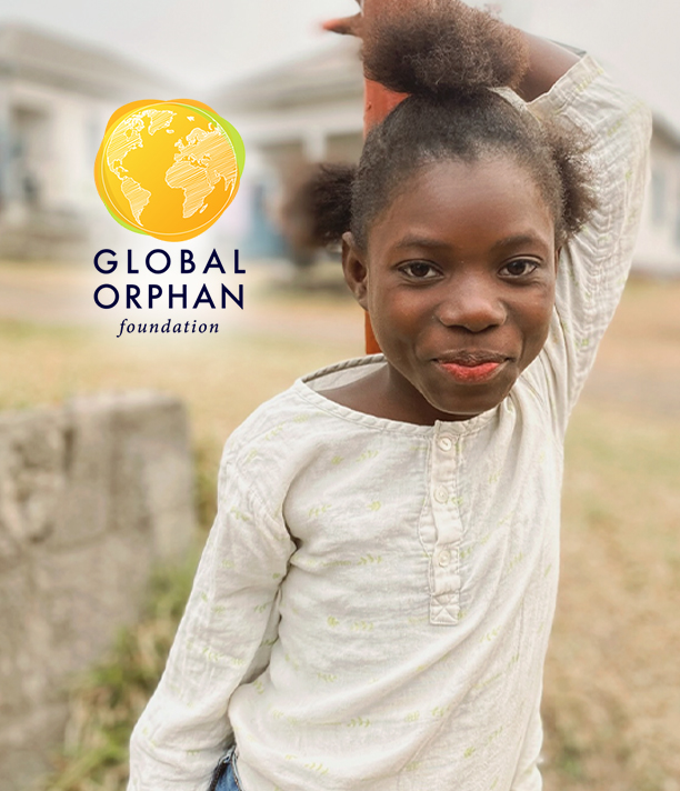 A young girl in a white shirt smiles softly outdoors, beside the Global Orphan Foundation logo.