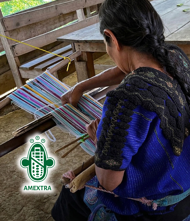A woman in an embroidered blouse weaves colorful thread on a traditional loom, beside the AMEXTRA logo.