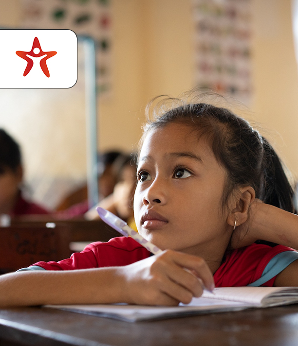 A girl in a red school shirt rests her head on her hand and gazes up thoughtfully in class, beside the ISF Cambodia logo.