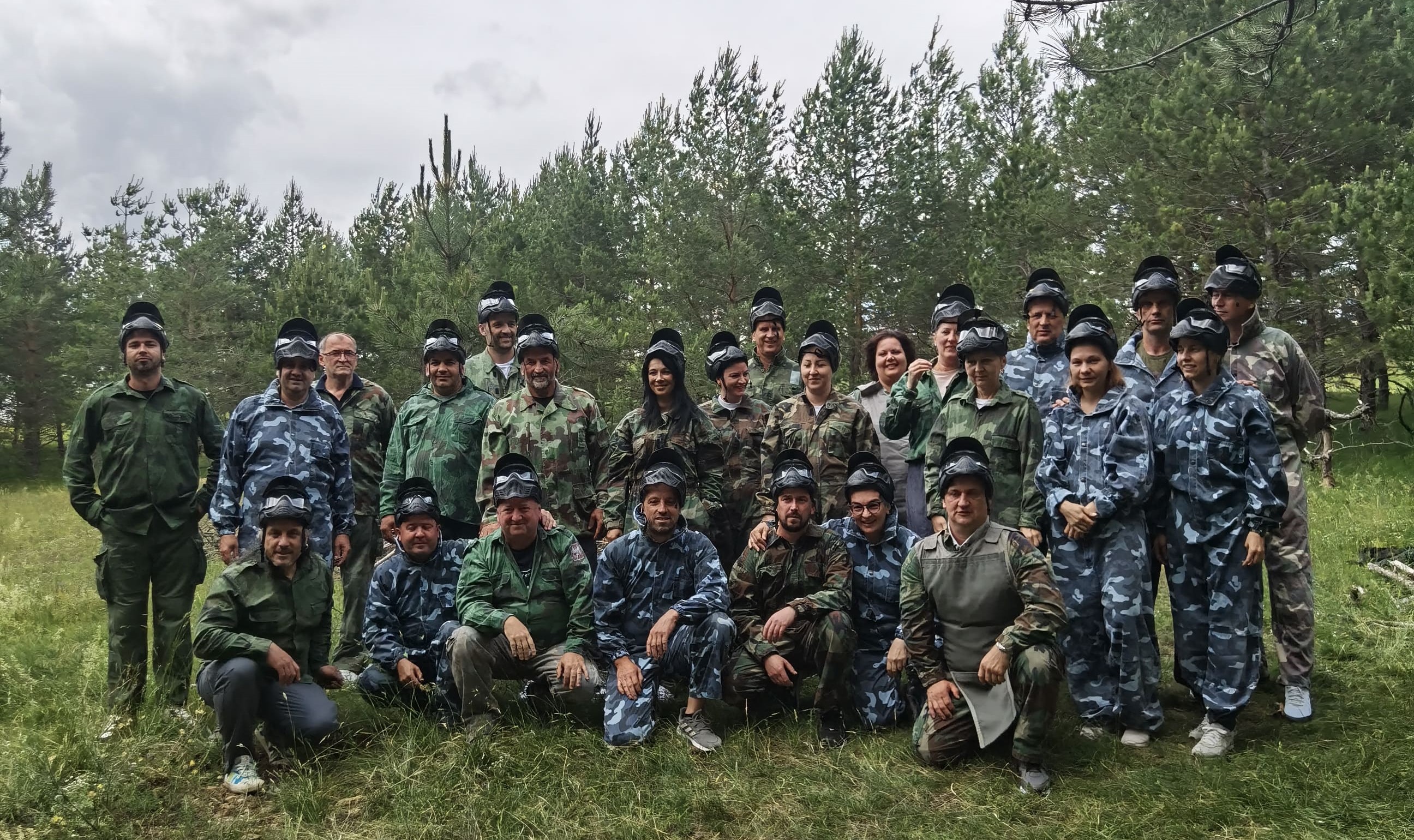 Ekipa nasmejana u opremi za paintball spremni za adrenalin koji pantball pruža.