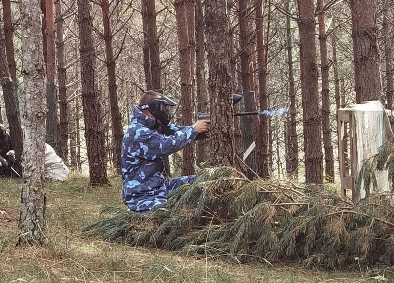 Čovek u opremi za paintball, puca na svoje protivnike i krije se iza prepreke.