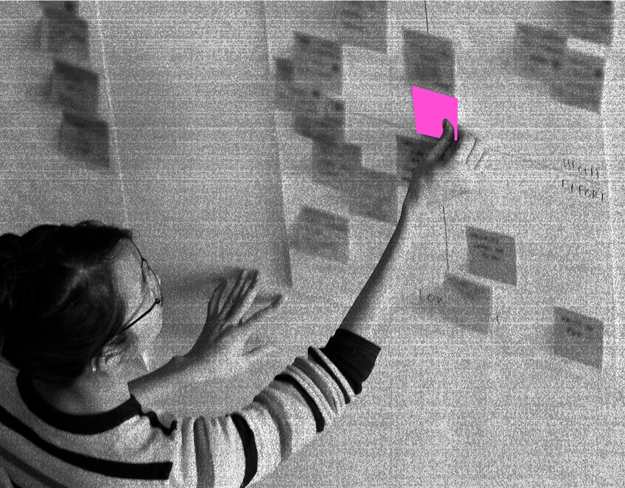 A workshop participant placing a sticky note on a wall covered in notes