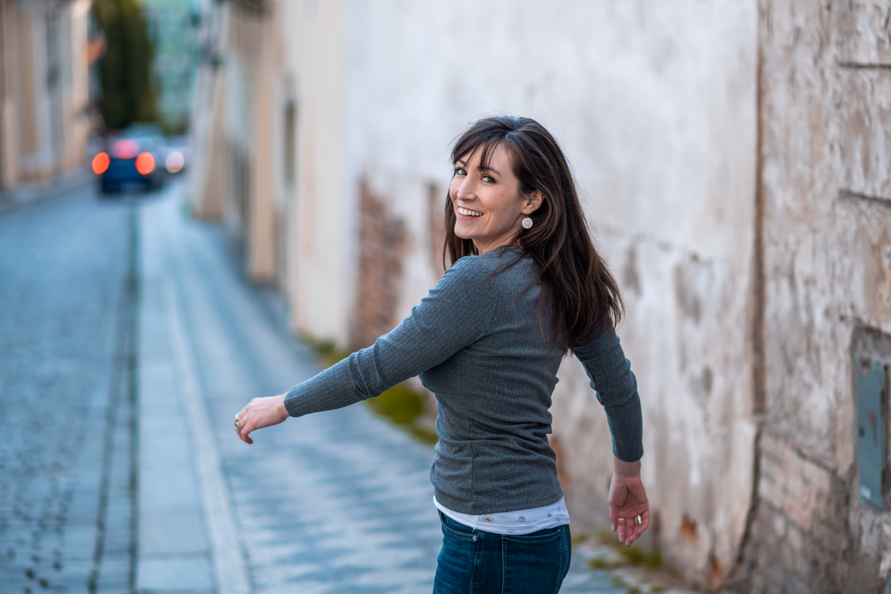 A photo of Juliann Beals - A UX Website Designer - smiling while walking on a cobblestone street. 