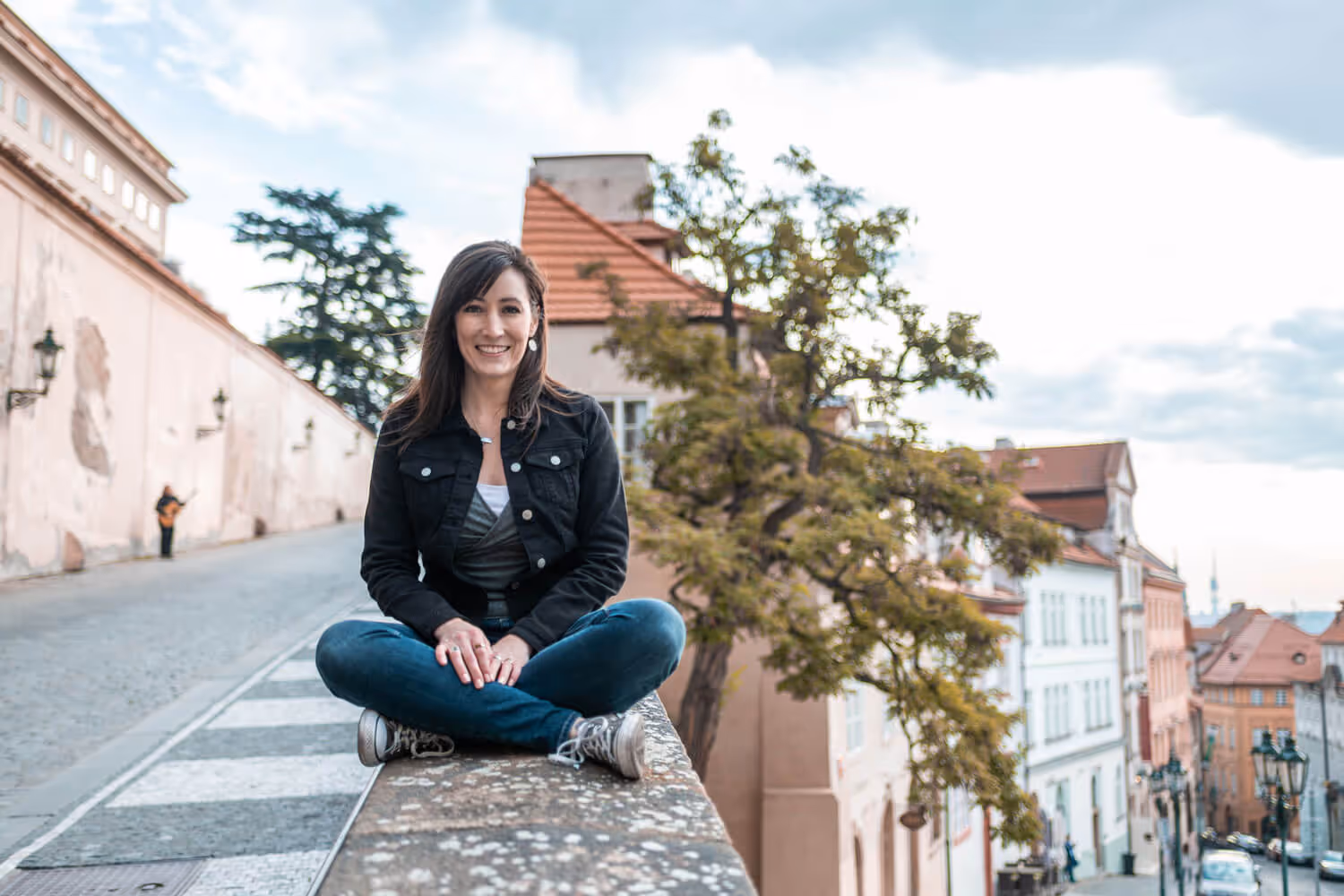 Juliann Beals - A UX Website Designer - posing for a photo, sitting on a wall in Prague. 