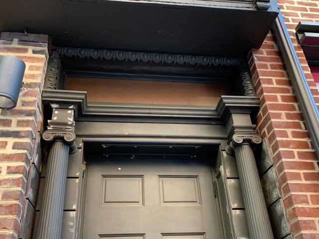 Restored historic doorway with ornate columns and decorative trim on brick building