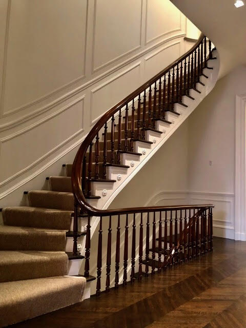 Custom curved wood staircase with handcrafted railing and balusters in elegant home