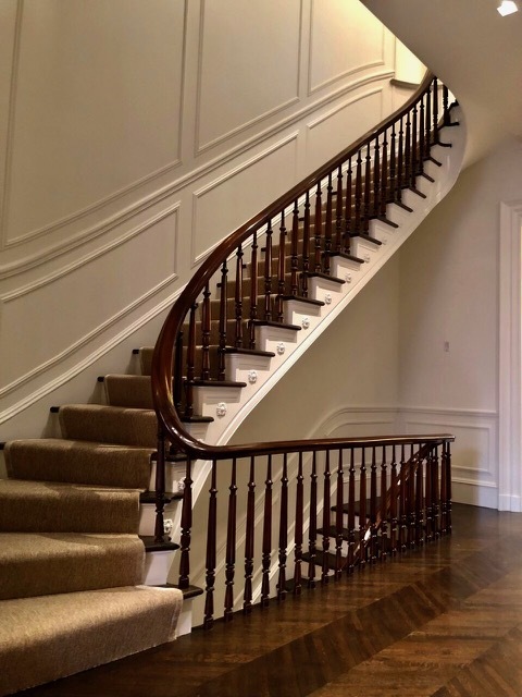 Curved staircase with carpet runner and wood balustrade
