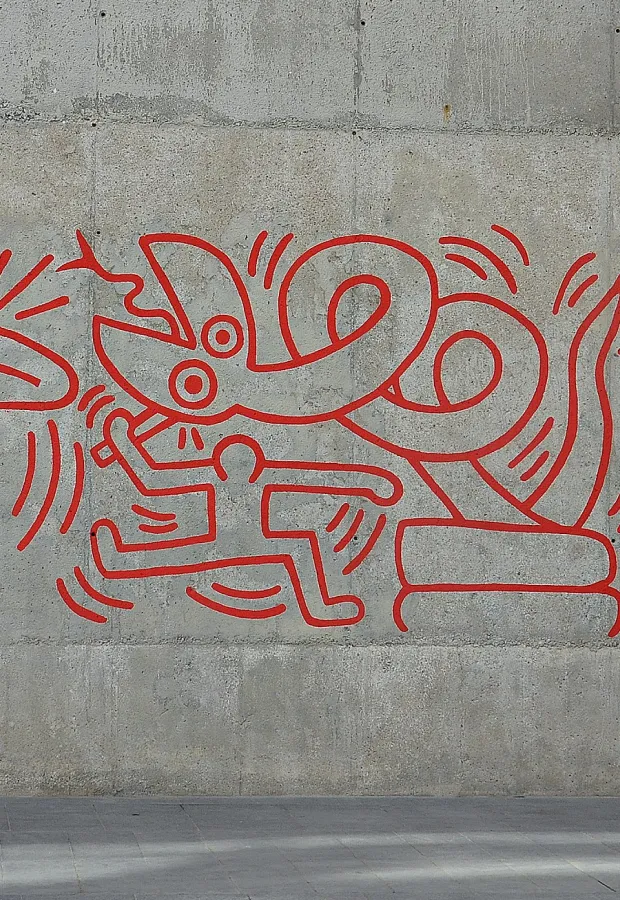 Red line drawing mural on a concrete wall depicting a person running away from a large serpent-like creature.