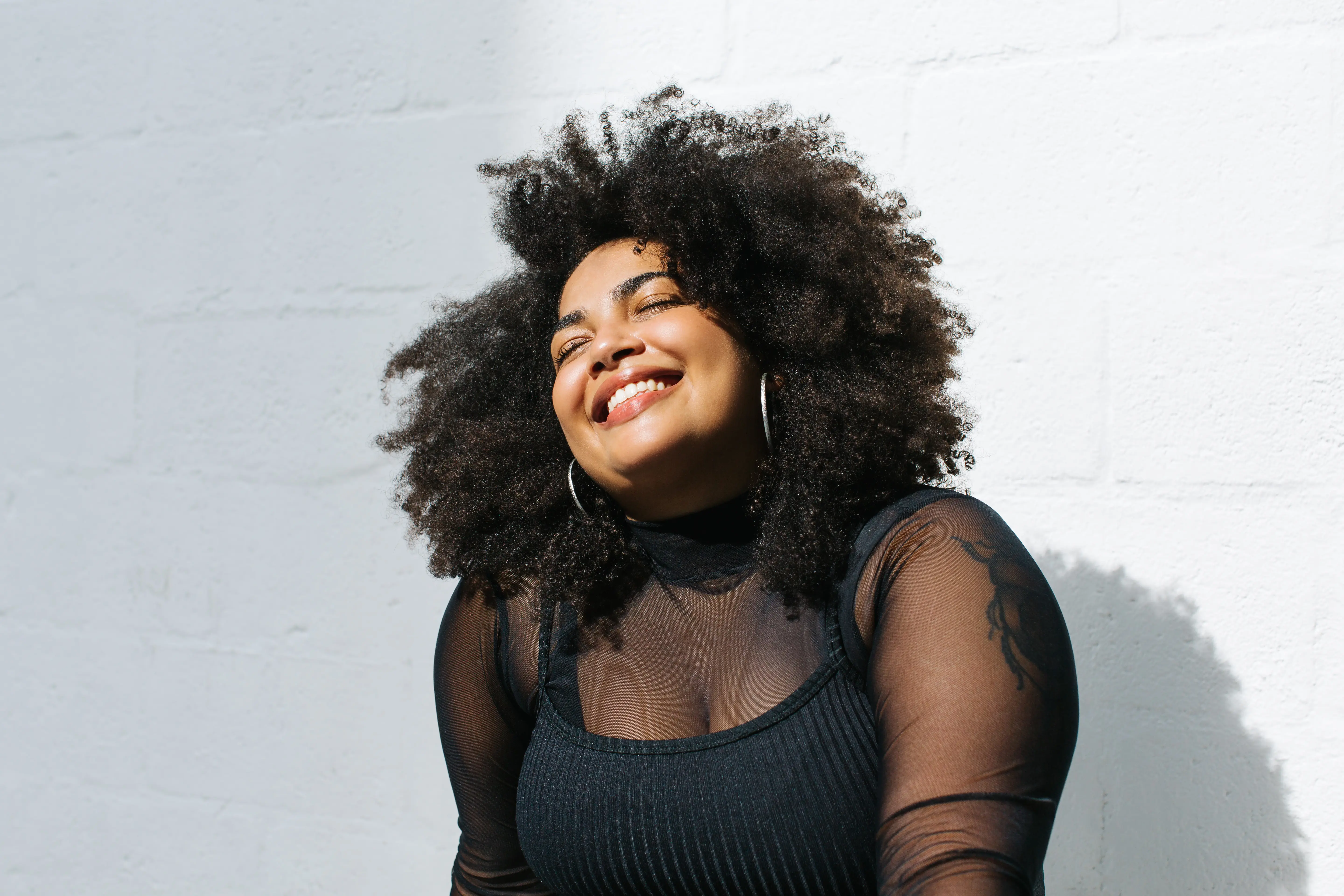 A woman with curly hair smiling and wearing a black top.