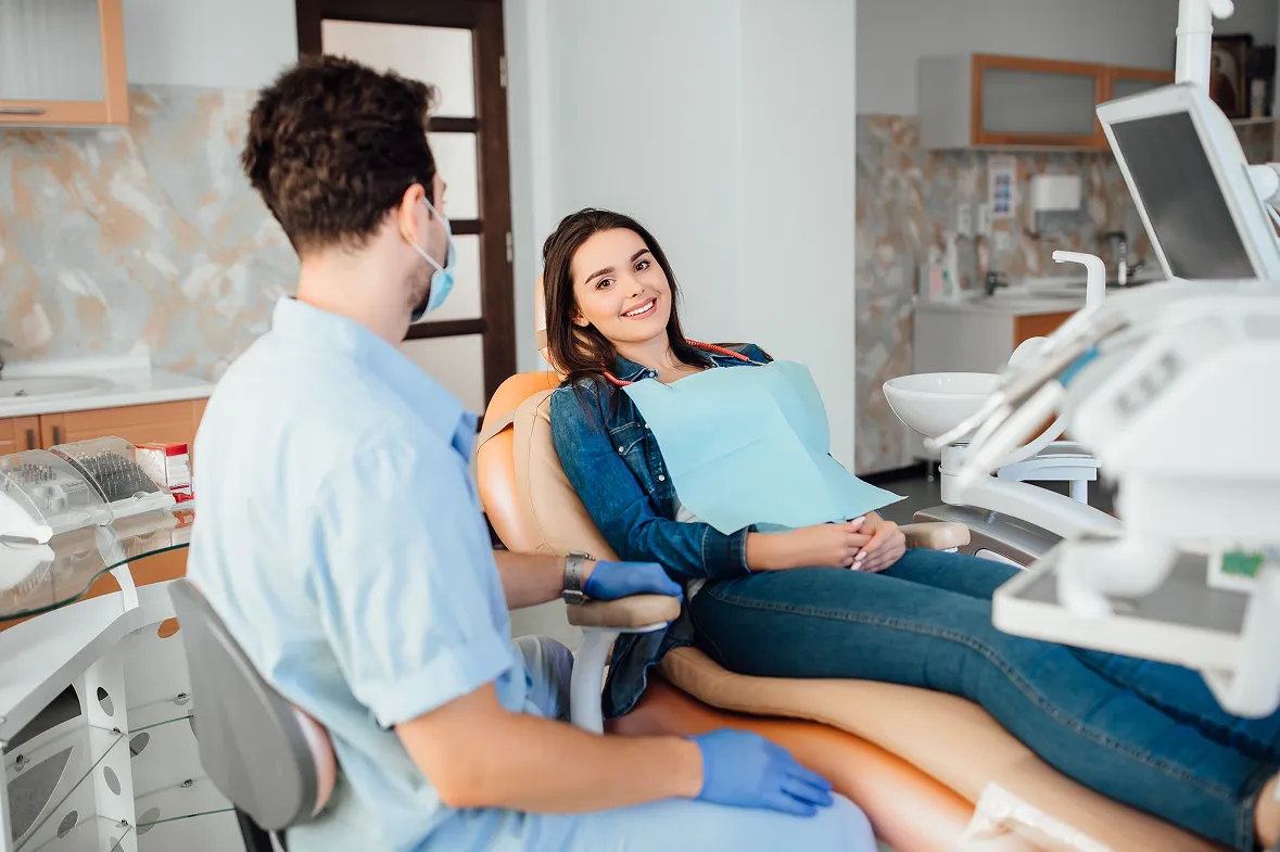 A woman sitting in a dental chair with a dentist.